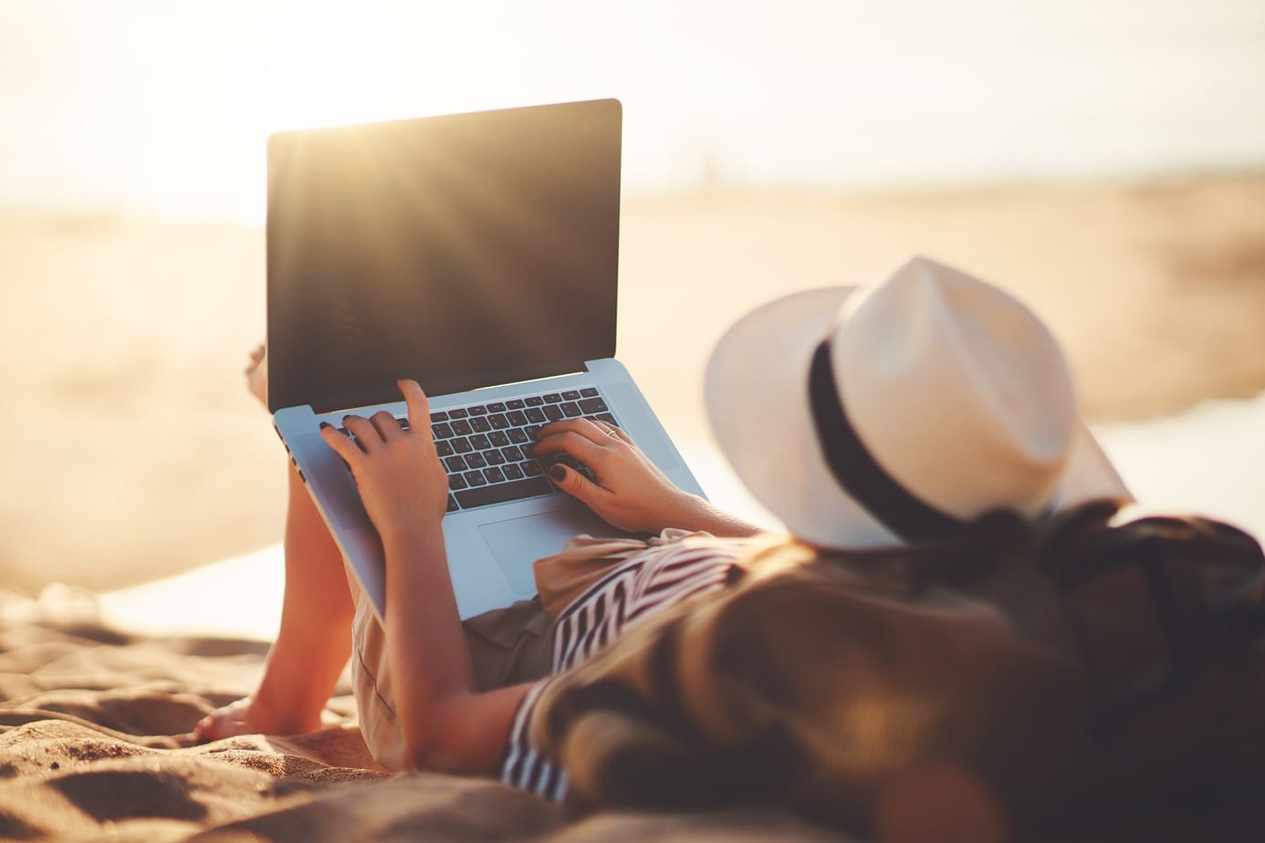 young woman working with laptop on nature in beach